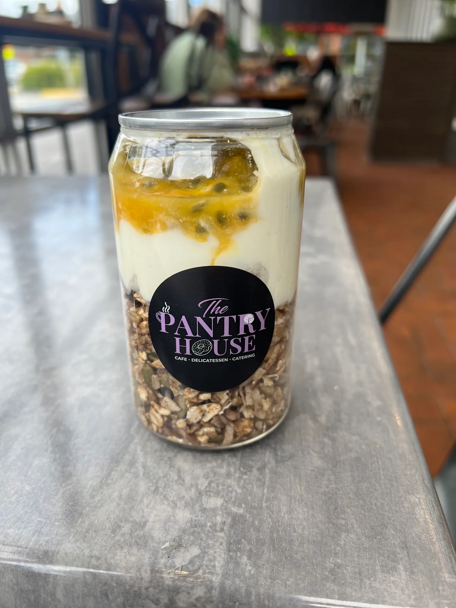 Pantry House branded bircher jar with granola, yoghurt and passionfruit on a café counter
