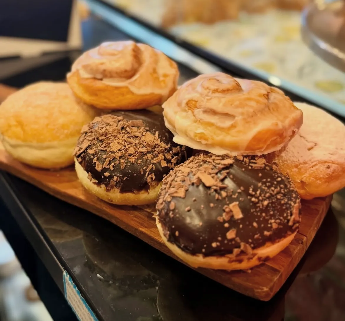 Chocolate doughnuts and cinnamon scrolls on a wooden board at the Pantry House café counter
